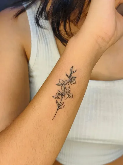 A beautiful fine-line floral tattoo on the forearm. This style is perfect for those who want a delicate and artistic piece that looks like a pen drawing on the skin.