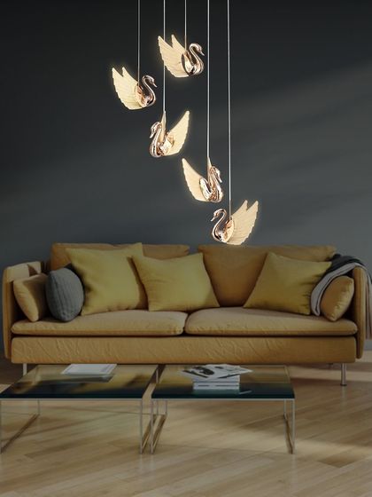 The swan chandelier adds a touch of elegance to this living room with a yellow sofa. The rose gold finish complements the warm tones in the room.