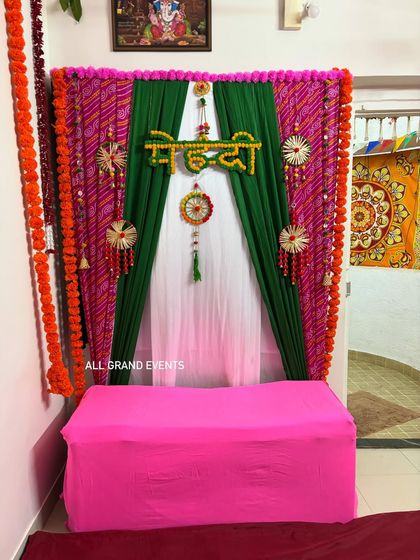 A clear, straight-on shot of the Mehendi backdrop. The combination of bright pink, rich green, and traditional orange marigolds makes for beautiful and vibrant photographs.