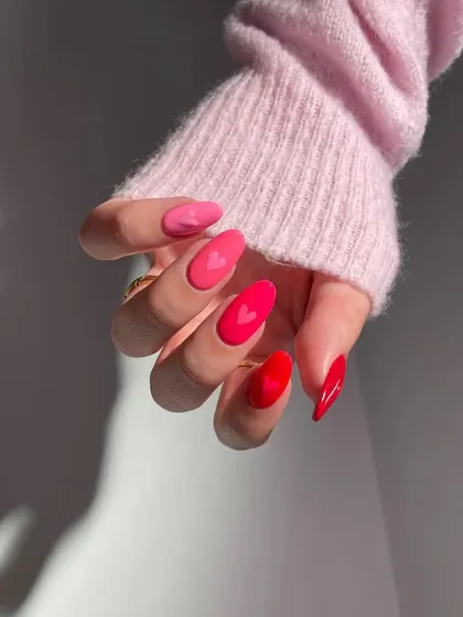 This shot captures the red and pink heart-themed nails from a different angle, showing how the design looks in motion and interacts with the light.