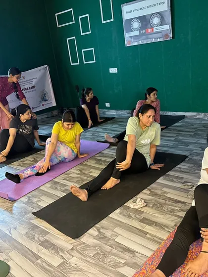 Celebrating International Yoga Day with a focused session. An instructor provides a hands-on adjustment to a student in a seated spinal twist. This ensures correct alignment and helps deepen the stretch safely.