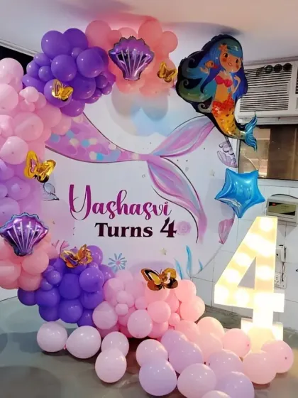 A magical mermaid-themed 4th birthday with a custom backdrop, organic balloon garland, and a large marquee number '4'.