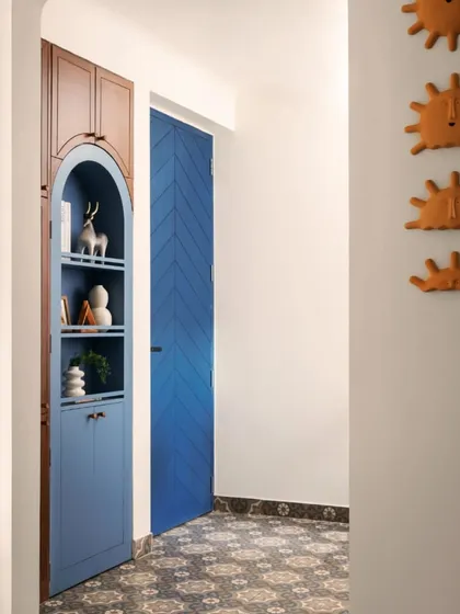 A closer look at the arched niche cabinet in the foyer. The combination of deep blue paint and warm wood provides a striking color contrast, turning a simple storage solution into a statement piece.
