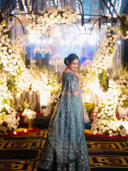 A beautiful shot of a powder blue floral lehenga, set against a backdrop of magical fairy lights, perfect for an evening sangeet.