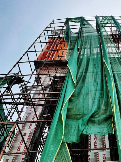 A dynamic shot looking up at the scaffolding and colourful facade panels of an upcoming school in Gurugram. It captures the energy and complexity of the construction process.