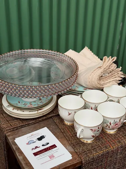 A collection of elegant tableware, including teacups, plates, and linens, prepared for our workshop. We teach you how to layer textures and patterns to create a cohesive and visually appealing tablescape.