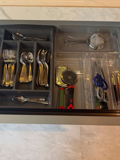 This cutlery drawer uses a pre-made tray to organize forks and spoons, with extra space for miscellaneous tools like scissors and a pizza cutter.