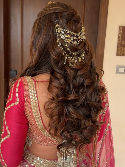 Voluminous curls with a beautiful, intricate hair accessory. This half-up style is perfect for adding a touch of glamour to any festive look.
