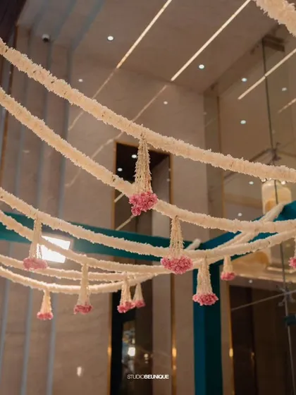 Cascading strings of jasmine and pink flowers hang from the ceiling, creating a fragrant and beautiful canopy for guests to walk under.