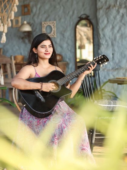 A collection of relaxed, bohemian-style portraits taken at a rustic cafe. The model is featured in a flowing paisley dress, interacting with props like a guitar, creating a natural and artistic vibe.