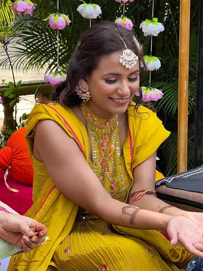 A candid moment of the bride getting her mehendi done, her makeup looking flawless.