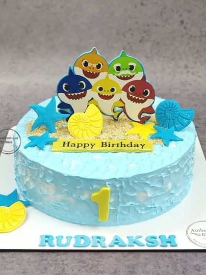A simple and cute Baby Shark cake for a first birthday. This buttercream cake is decorated with the shark family, starfish, and shells, perfect for a little one's celebration.