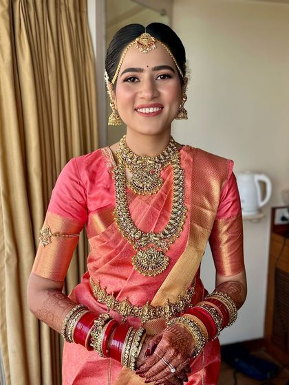 A frontal portrait showcasing the beautiful symmetry of the makeup and jewellery. The look is quintessentially South Indian: radiant, elegant, and deeply rooted in tradition.