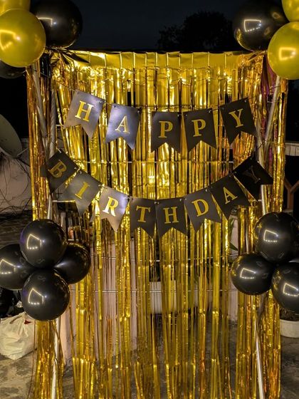 A simple terrace decoration featuring a gold foil curtain and a black and gold "Happy Birthday" banner.