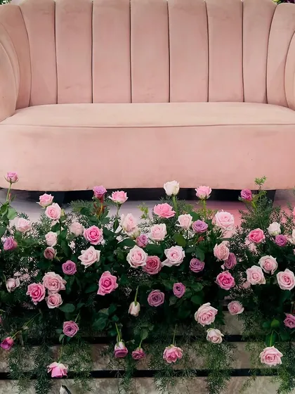 A close-up of the floral work at the base of a stage. I use a variety of fresh roses in shades of pink, nestled in lush greenery, to add a touch of natural beauty and elegance to the main seating area.