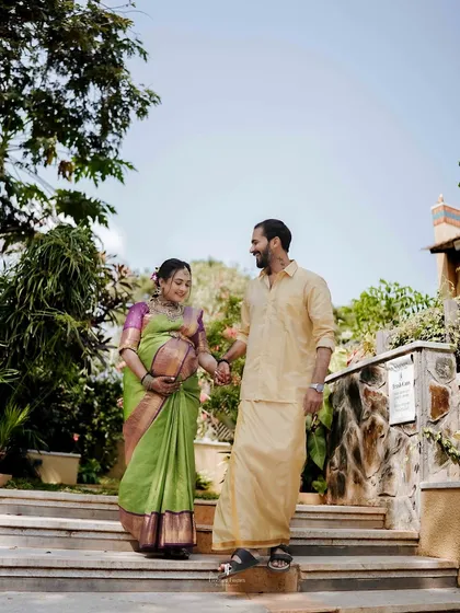 A beautiful couple's portrait during their outdoor maternity session. Dressed in traditional attire, they walk hand-in-hand, celebrating their journey to parenthood amidst a lush garden setting.