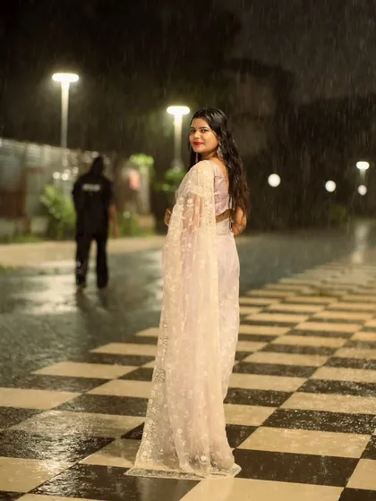 An over-the-shoulder glance from the same rainy night shoot. The glistening wet ground and soft lights create a magical atmosphere.