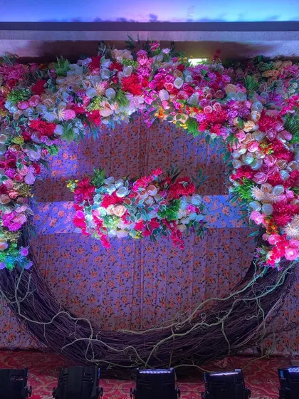 A close-up of the floral moon-gate stage, showing the rich texture of the flowers against the patterned backdrop.