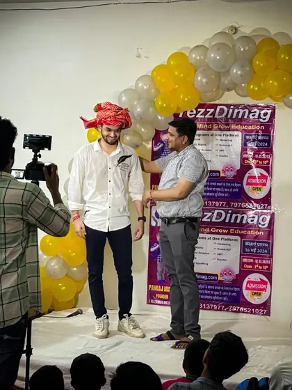 Our camera crew filming as I am being welcomed on stage in Kotputli. We document our journey to share the energy and impact of our educational movement with a wider audience.