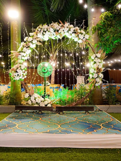 A beautiful photo spot with a circular floral arch and hanging fairy lights. This setup, placed in a garden, provides a magical and romantic backdrop for evening photos.