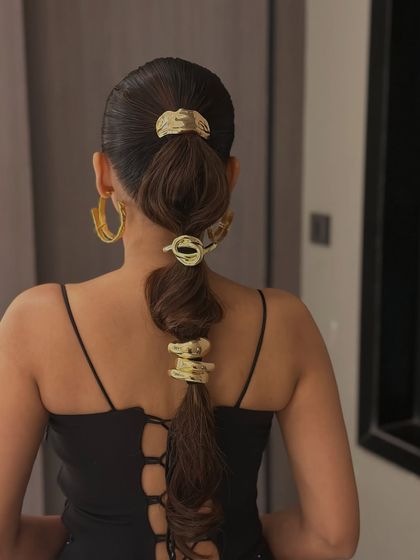 A close-up of the unique gold hair cuffs used in this stylish ponytail.