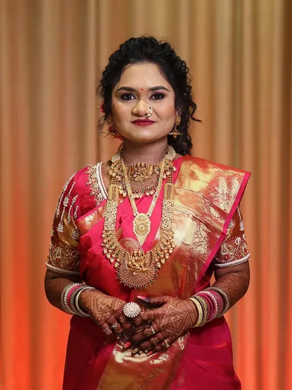 A portrait of a real bride on her wedding day. Her look features soft curls, glowing skin, and traditional gold jewelry, creating a look of pure elegance.