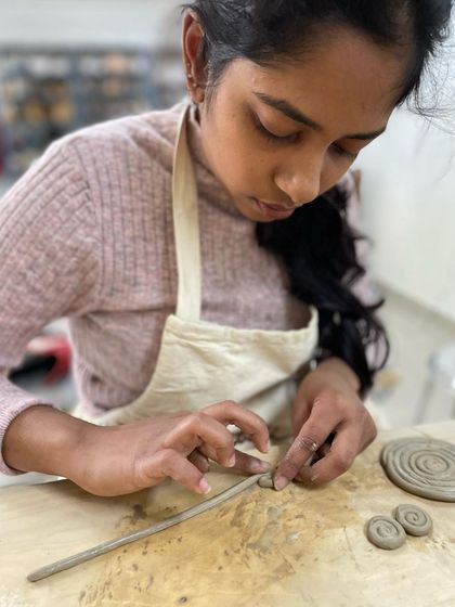 Another example of coiling, where a student carefully rolls and attaches small spirals to their piece. It's a technique that allows for endless creativity.