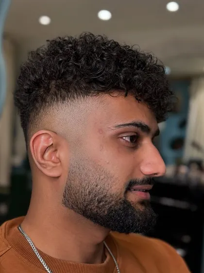 This is what we do best. A perfect high fade blended into natural curls, finished with a sharp beard line-up. It's a modern, clean, and stylish look.
