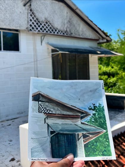 Holding up my finished painting against the building in Auroville. It's my way of taking a piece of the place with me.
