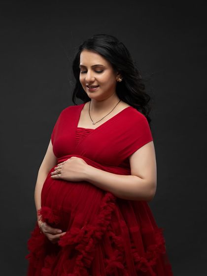 A close-up showing the soft fabric and neckline of the red ruffled gown, perfectly framing her happy and peaceful expression.