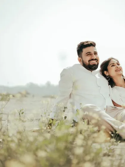 A couple relaxes in a sun-drenched field, showcasing the serene and natural side of our location. It's a perfect spot for casual, light-hearted, and romantic photos.