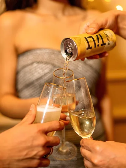 An action shot of Tilt wine being poured into champagne flutes. This image elevates the canned wine by associating it with classic celebration rituals, blending convenience with sophistication.