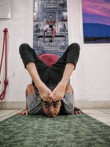 Our advanced batches prepare students for yoga competitions. This student is practicing a complex forward bend, showcasing focus and control.