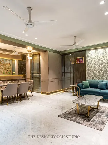 A complete view of the open-plan living and dining area, demonstrating a seamless flow between the two zones. The design balances modern furniture with traditional Indian art, reflecting a contemporary yet rooted aesthetic.