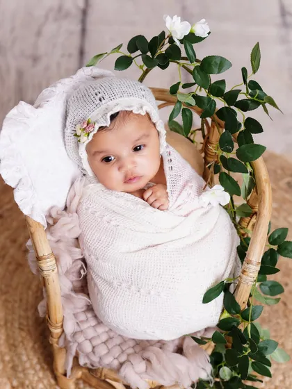 This is why I adore newborn photography. This peaceful baby is swaddled in soft white fabric, nestled in a rustic basket with delicate greenery, creating a pure and natural portrait.