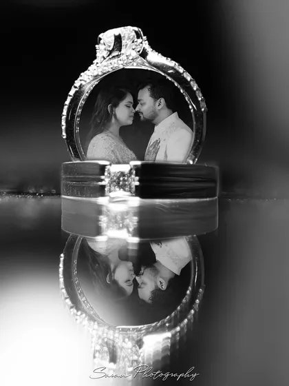 An artistic shot of the wedding rings, with the couple's reflection captured within. We believe in creative product photography that turns details like jewelry into a piece of the narrative.