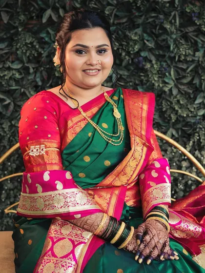 Prajakta's wedding look in her green and pink Paithani. The makeup was designed to complement the vibrant colors of her saree, with a focus on glowing skin and softly defined eyes.