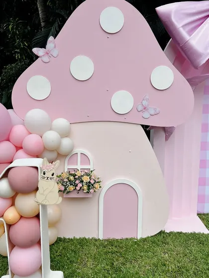 The magic is in the details. This close-up of our 'Bow & Bunny' theme shows a custom-built, life-sized mushroom house prop, complete with a window box of flowers and delicate butterfly accents, perfect for a whimsical first birthday.