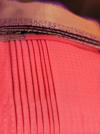 A close-up of the pleats on the coral pink saree.