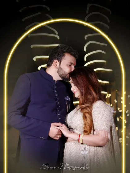 A creative couple portrait with a neon arch, capturing a tender forehead kiss during their engagement celebration.