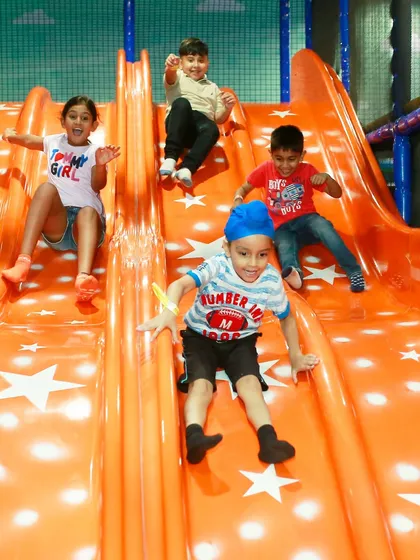 A dynamic shot of four friends sliding down together, each with a joyful expression. Our wide slides are perfect for group fun.