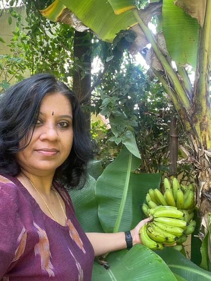 A happy customer showing off her banana harvest. Gardening is a powerful form of self-care, and harvesting your own fresh produce provides both better nutrition and a sense of accomplishment.
