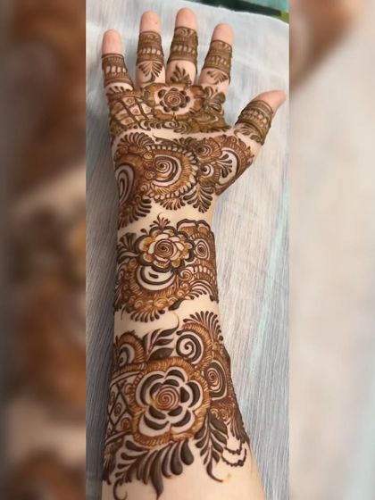 A side view of a full-arm henna design. This angle shows how the floral and vine patterns gracefully wrap around the arm, creating a continuous flow of art.