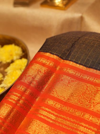 A close-up of the rich orange border with its traditional peacock and paisley motifs.