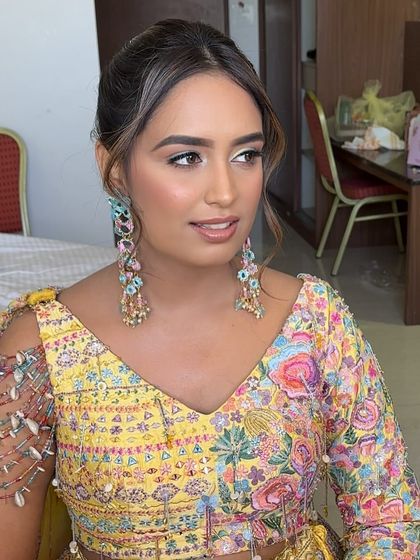 A portrait of the client, showing her fresh makeup and the simple, stylish ponytail that keeps the focus on her colorful outfit and earrings.