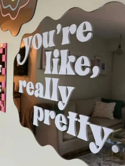 Add a personal touch to your room with a custom quote mirror. This piece features a trendy wavy shape and the phrase 'you're like, really pretty' in a bold font, turning a daily affirmation into decor. We can create any shape and apply any text or design you envision.