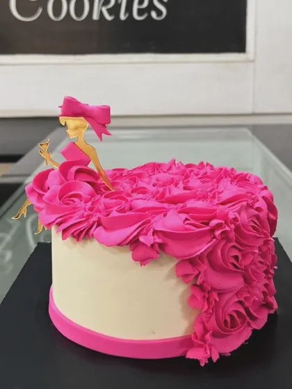 An elegant cake with a cascade of vibrant pink buttercream rosettes, topped with a stylish silhouette.