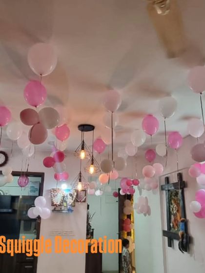 Loose balloons on the ceiling create a simple yet festive atmosphere for a 'Welcome Baby Girl' home celebration.