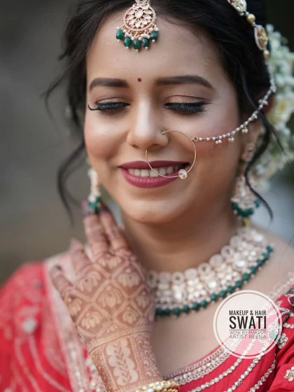 A close-up of Amruta's bridal beauty. The focus is on her intricate henna, the classic nath, and the beautiful smile on her face.