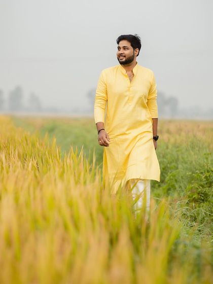 The groom takes a walk through a paddy field, his yellow kurta perfectly matching the pre-wedding festive atmosphere.